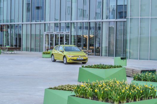 Gul Volkswagen Golf och blomrabatter
