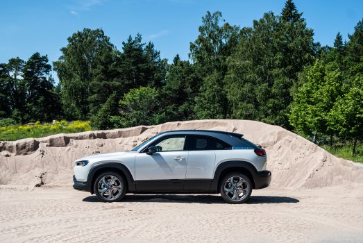 En vit Mazda MX-30 från sidan, framför sand