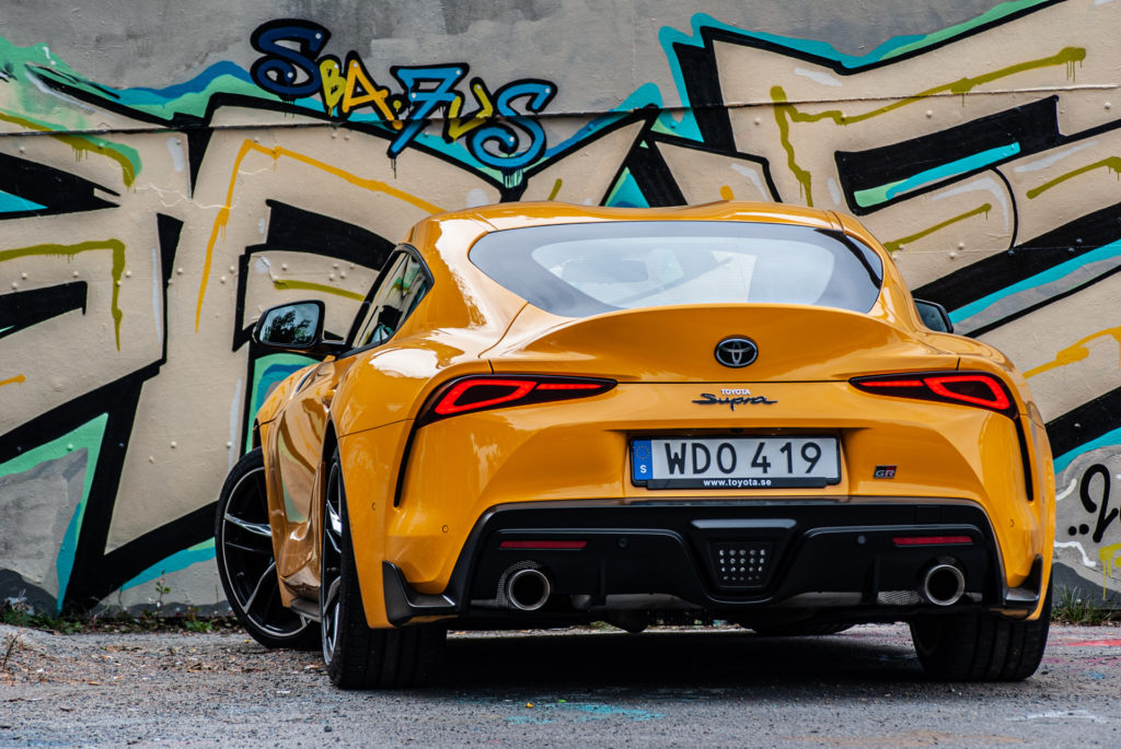Gul Toyota GR Supra sedd bakifrån vid graffitivägg
