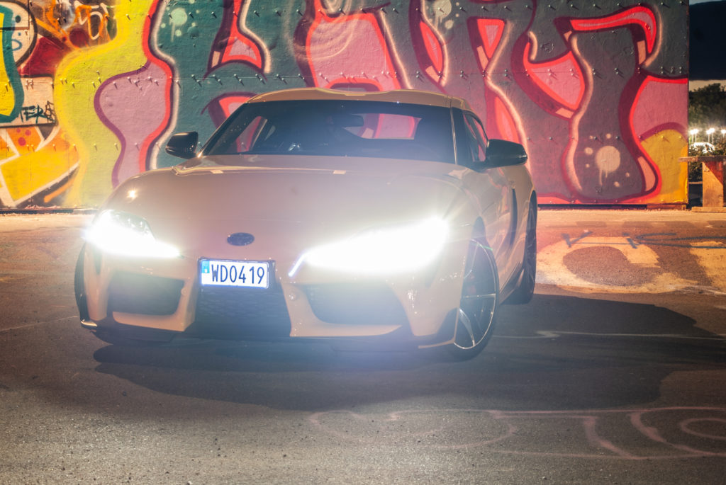 Gul Toyota GR Supra med strålkastarna på